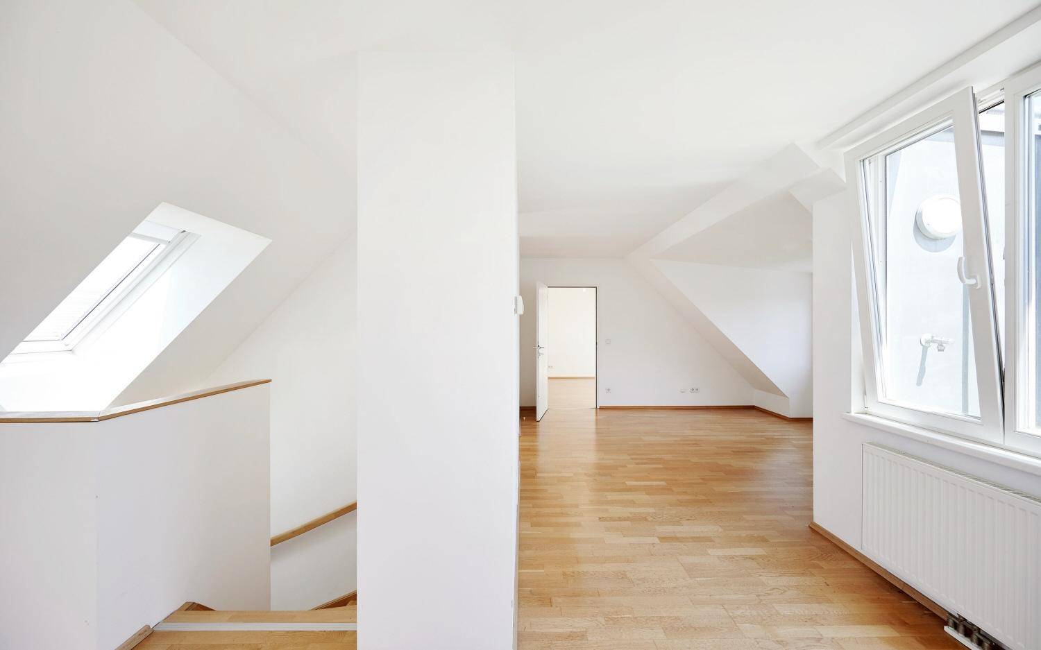 Heller Flur im Dachgeschoss mit Holztreppe und Dachfenster, führt zu weiteren Räumen.