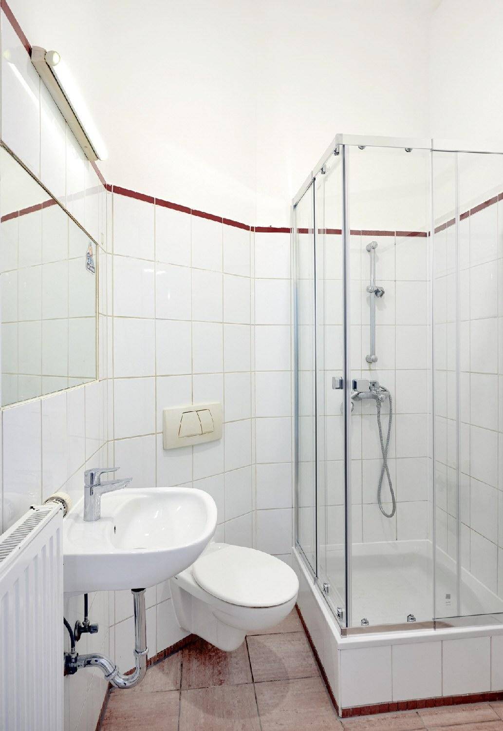 Modernes Badezimmer mit Duschkabine, Waschbecken und WC, hell gefliest und funktional.