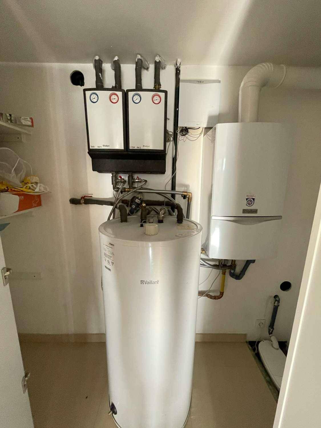 Technikraum mit Warmwasserspeicher und Heizungsinstallationen, sauber und gut organisiert.