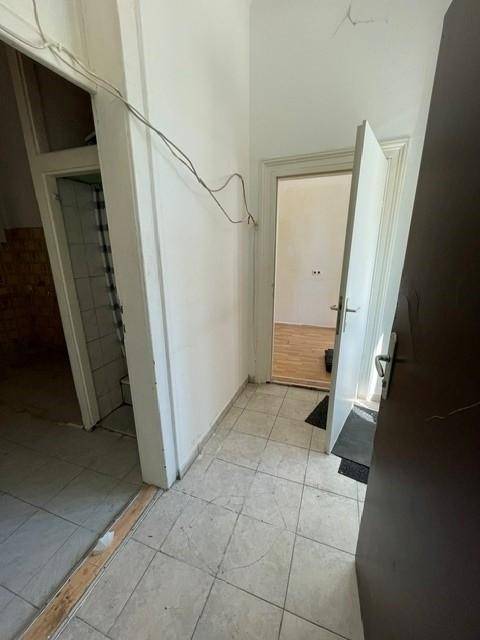 Flur mit Fliesenboden und Zugang zu verschiedenen Räumen, mit sichtbaren Kabeln an der Wand.