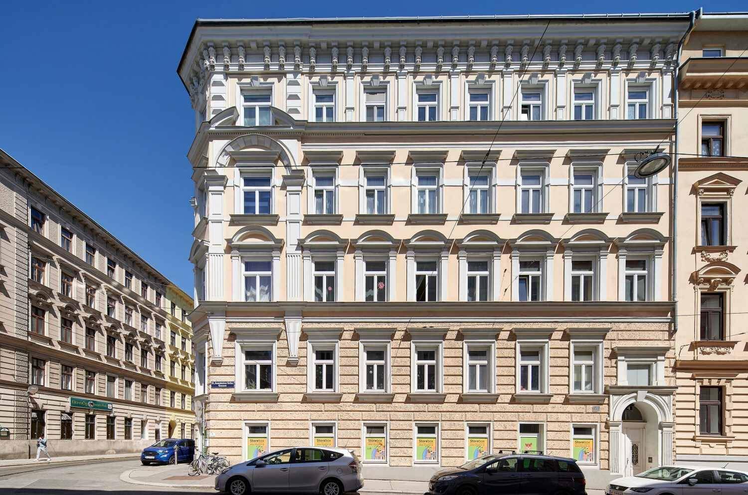 Elegantes Altbaugebäude mit detailreicher Fassade und Fenstern, an einer belebten Straße gelegen.