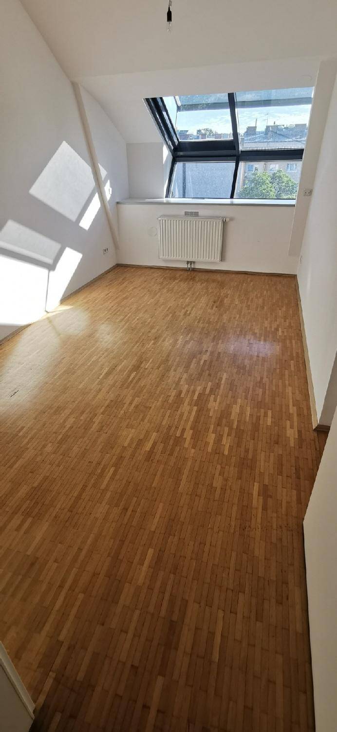 Lichtdurchflutetes Zimmer mit Holzparkett und Dachfenster, ideal als Schlaf- oder Arbeitszimmer.