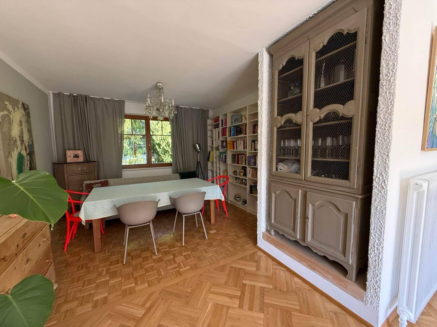 Essbereich mit großem Holztisch, Bücherregal und Blick ins Grüne.