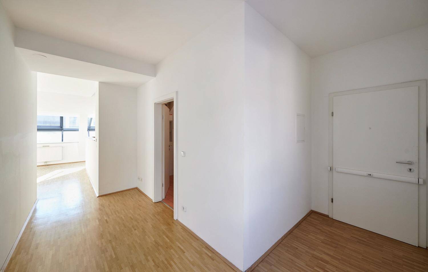 Heller Flur mit Holzboden und Zugang zu verschiedenen Räumen der Wohnung.