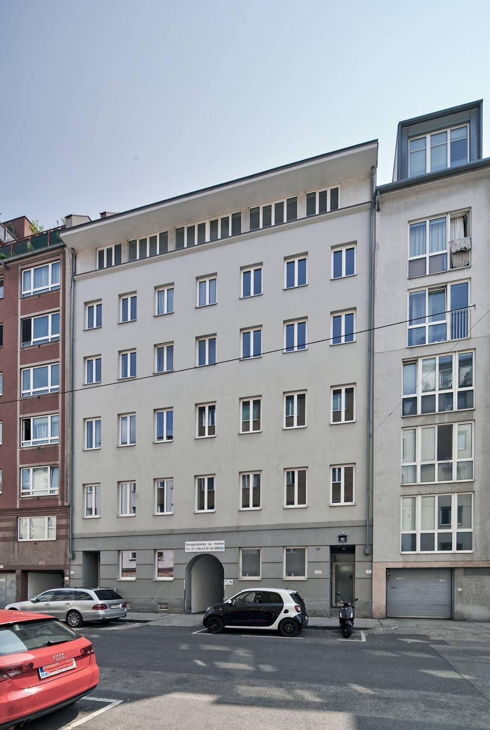 Fassade eines Wohngebäudes mit geparkten Autos auf der Straße.