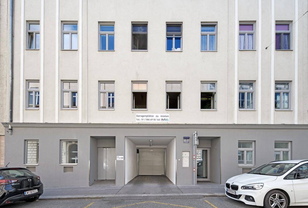 Vorderansicht des Gebäudes mit Garageneinfahrt und Haupteingang direkt an der Straße.