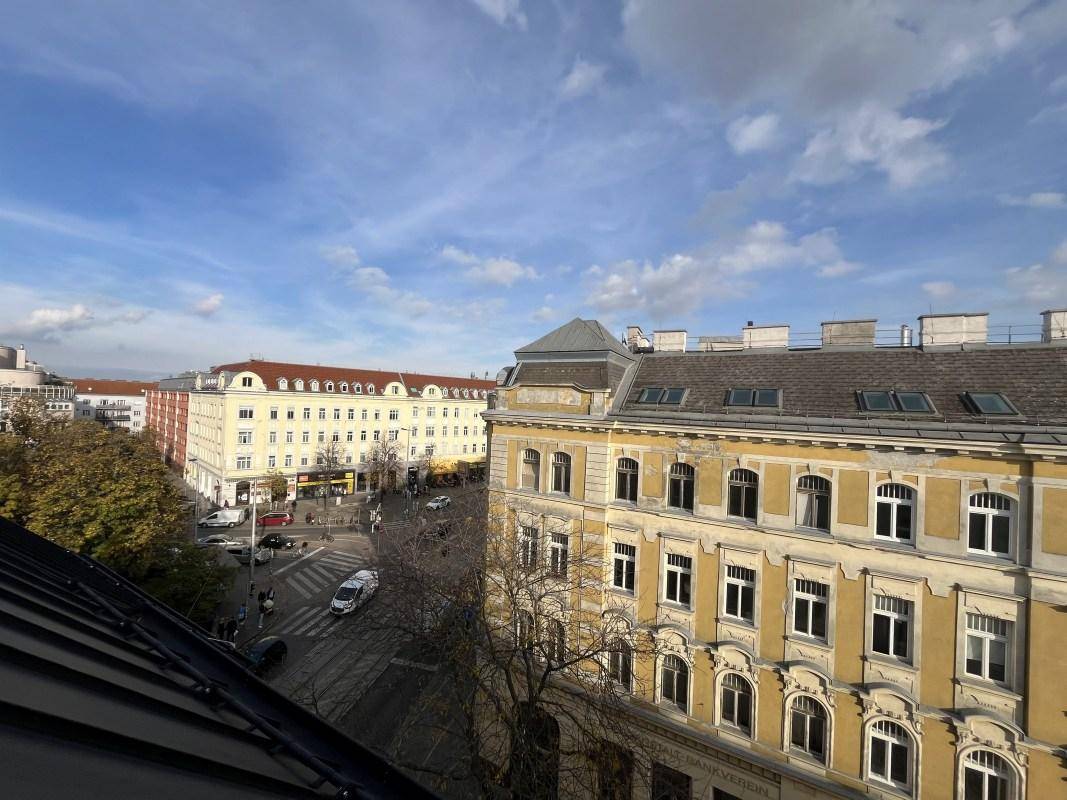 Weitläufiger Stadtblick über Dächer und Straßen an einem sonnigen Tag.