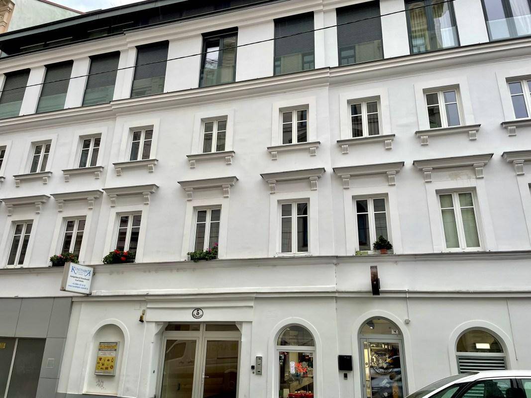 Nahaufnahme der weißen Fassade eines Stadthauses mit vielen Fenstern und Fensterläden.