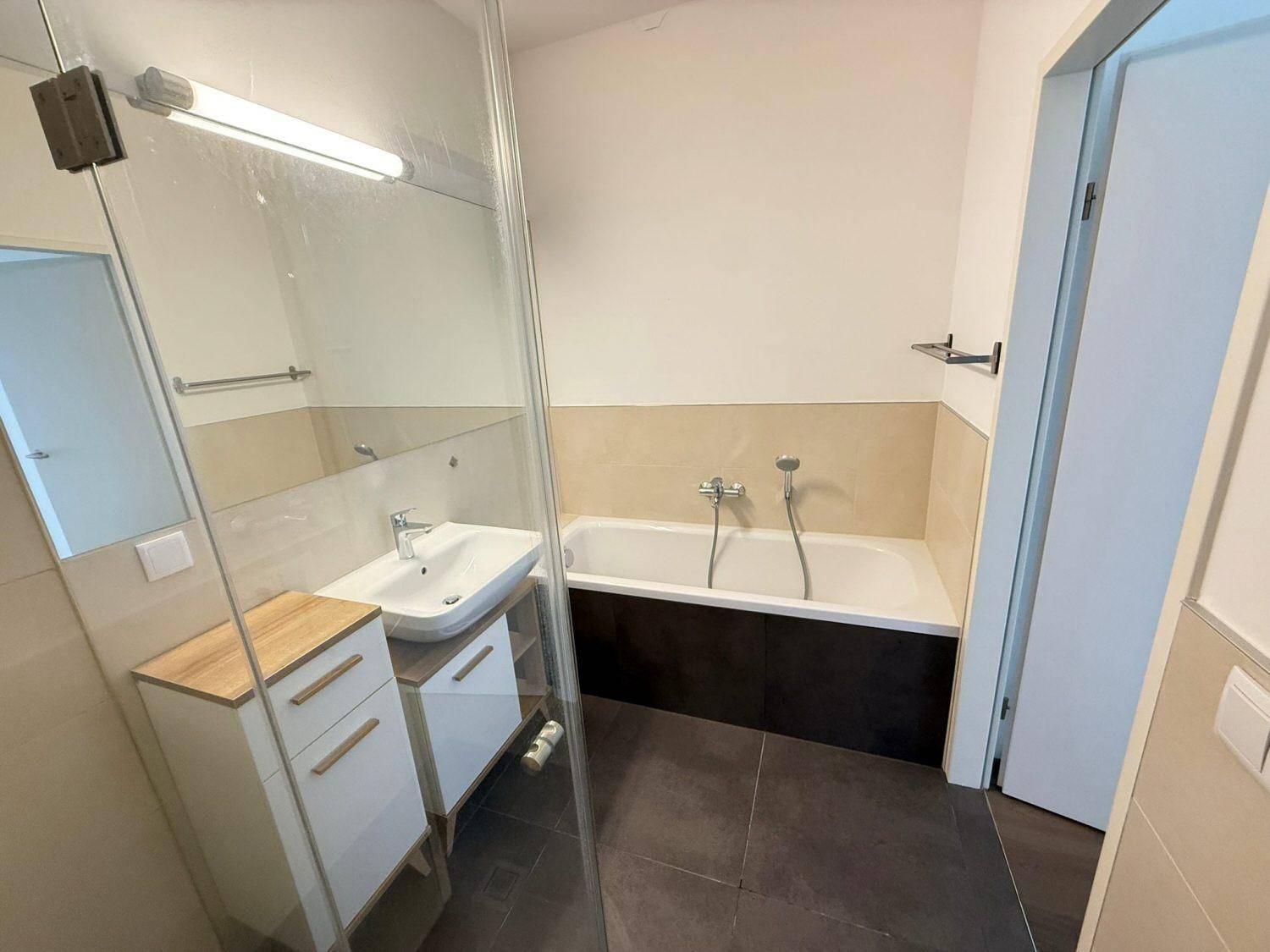 Modernes Badezimmer mit Badewanne, Duschabtrennung und Waschtisch mit Unterschrank.