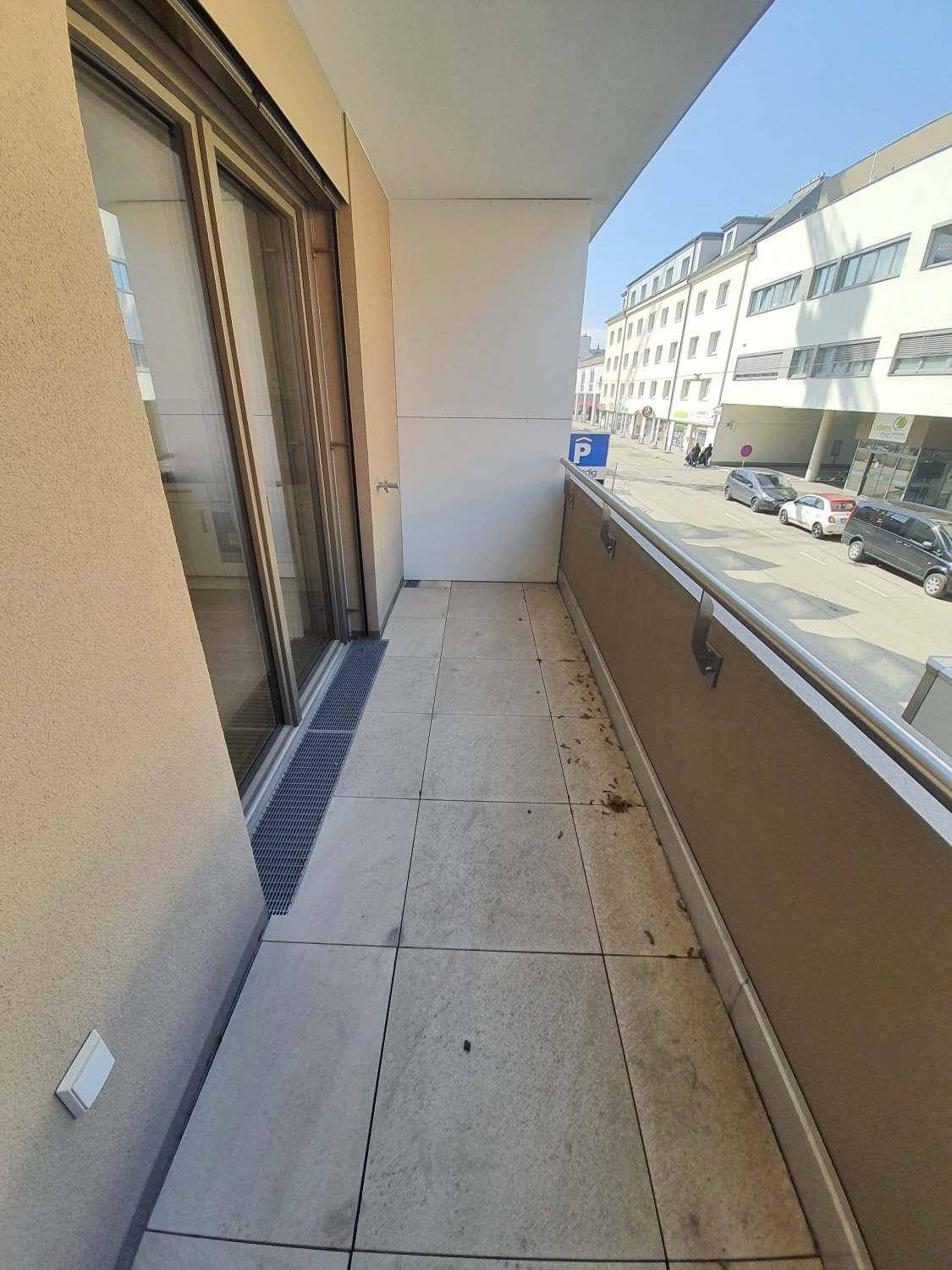 Heller Balkon mit Fliesenboden und Blick auf die umliegende Stadtstraße.
