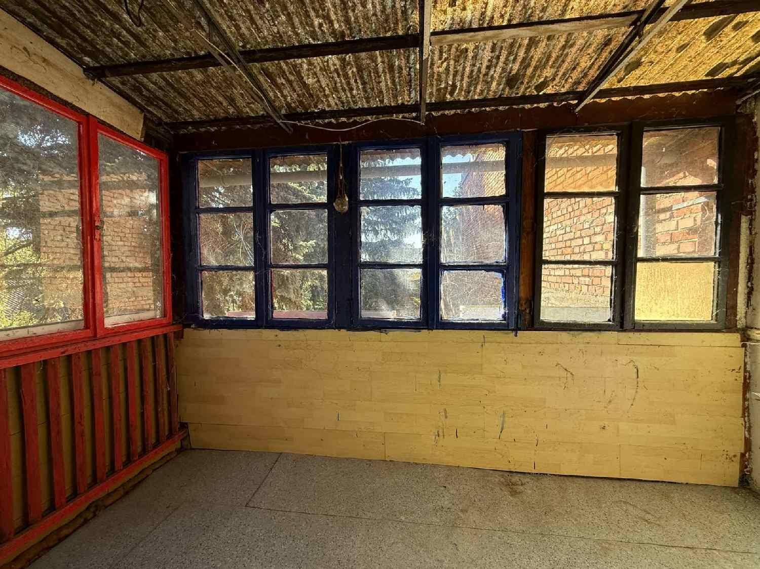 Verglaster Anbau mit vielen Fenstern und Wellblechdach, als Wintergarten nutzbar.