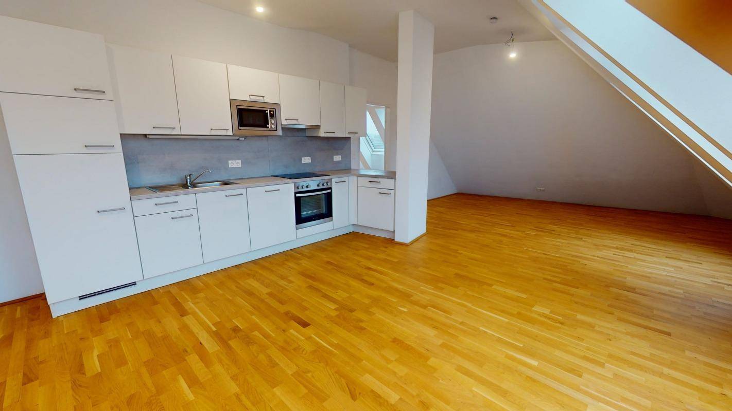 Moderne Einbauküche mit weißen Schränken und Holzboden in einem offenen Raum.
