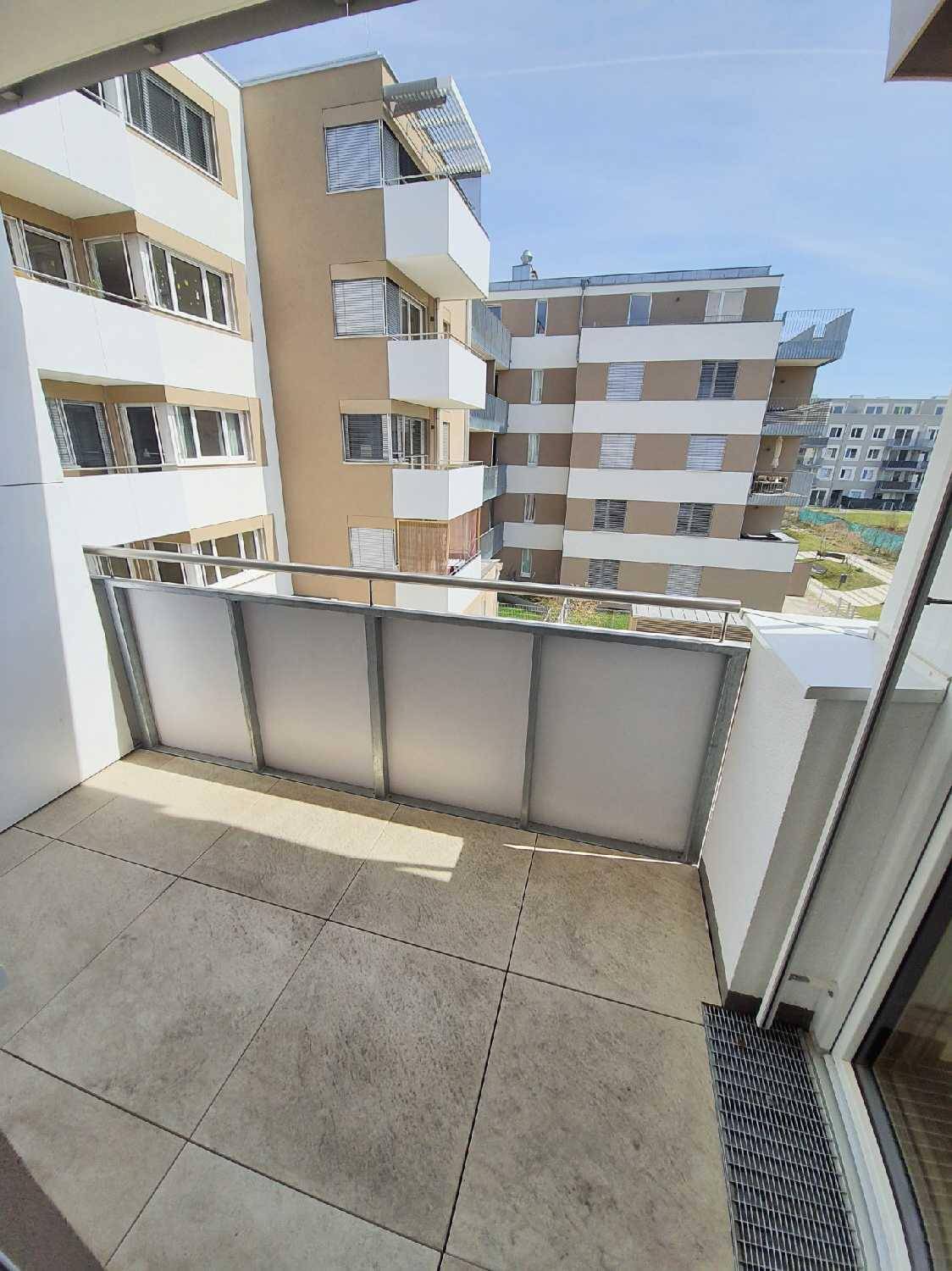 Geräumiger Balkon mit Fliesenboden und Blick auf die umliegenden Wohngebäude.