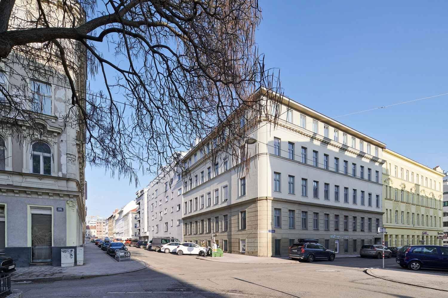 Straßenansicht eines Wohngebäudes in einer städtischen Umgebung mit parkenden Autos.