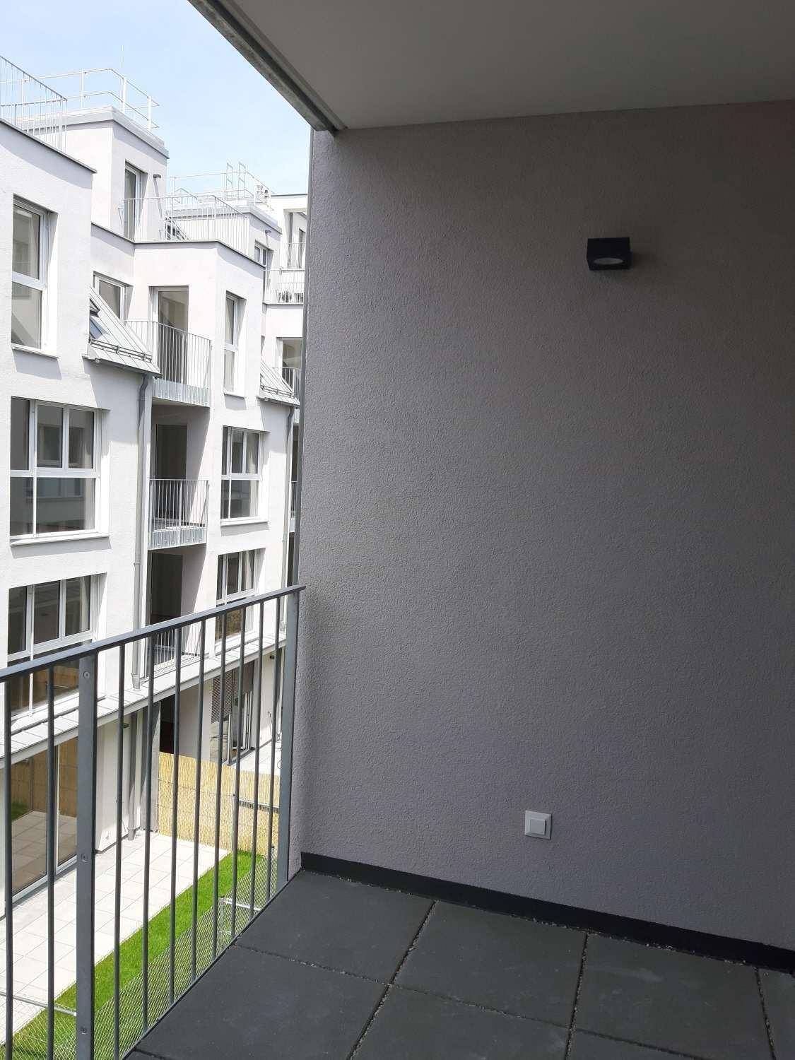 Balkon mit Fliesenboden und Blick auf den Innenhof des Gebäudes.