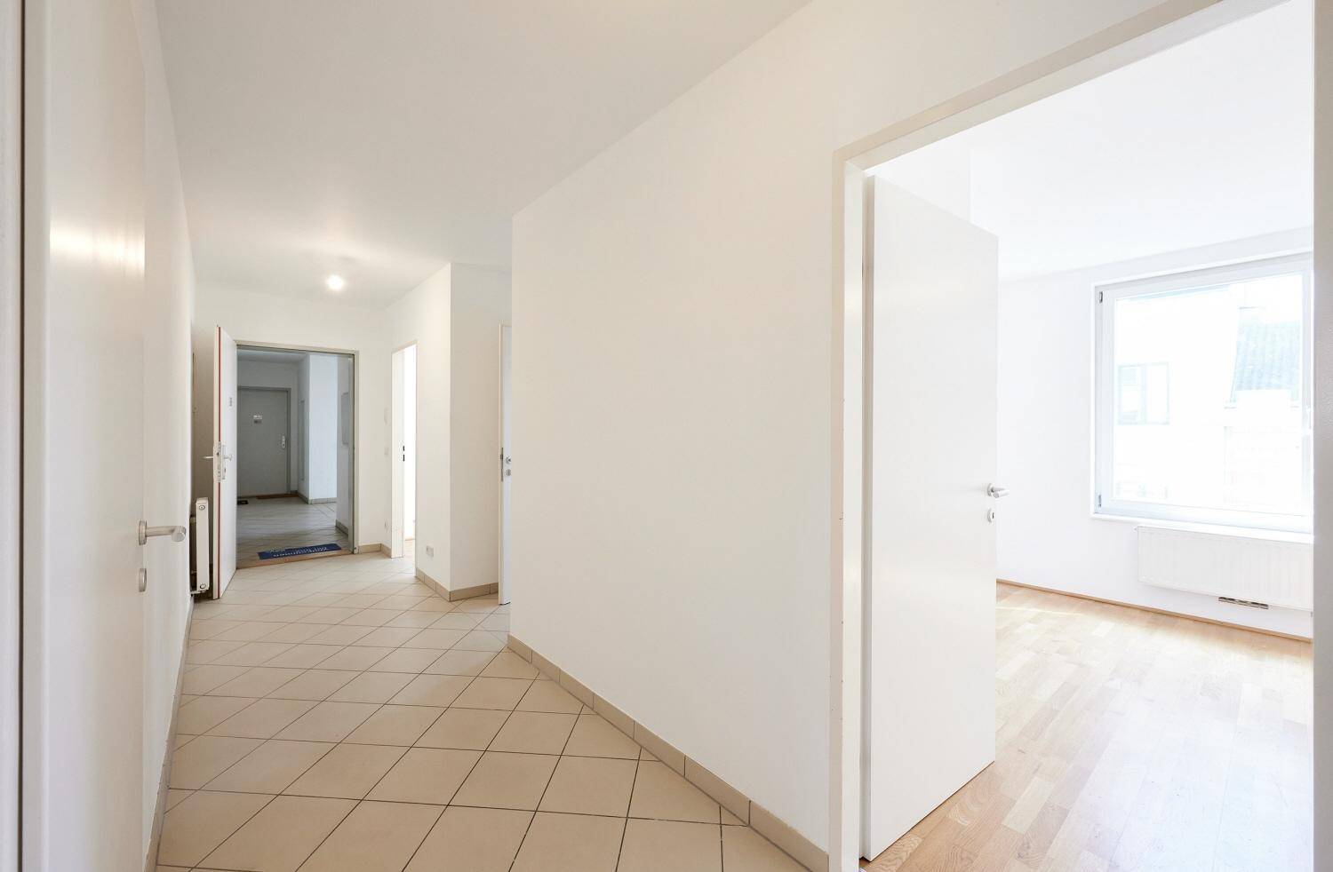 Heller Flur mit Fliesenboden, der zu weiteren Räumen der Wohnung führt.