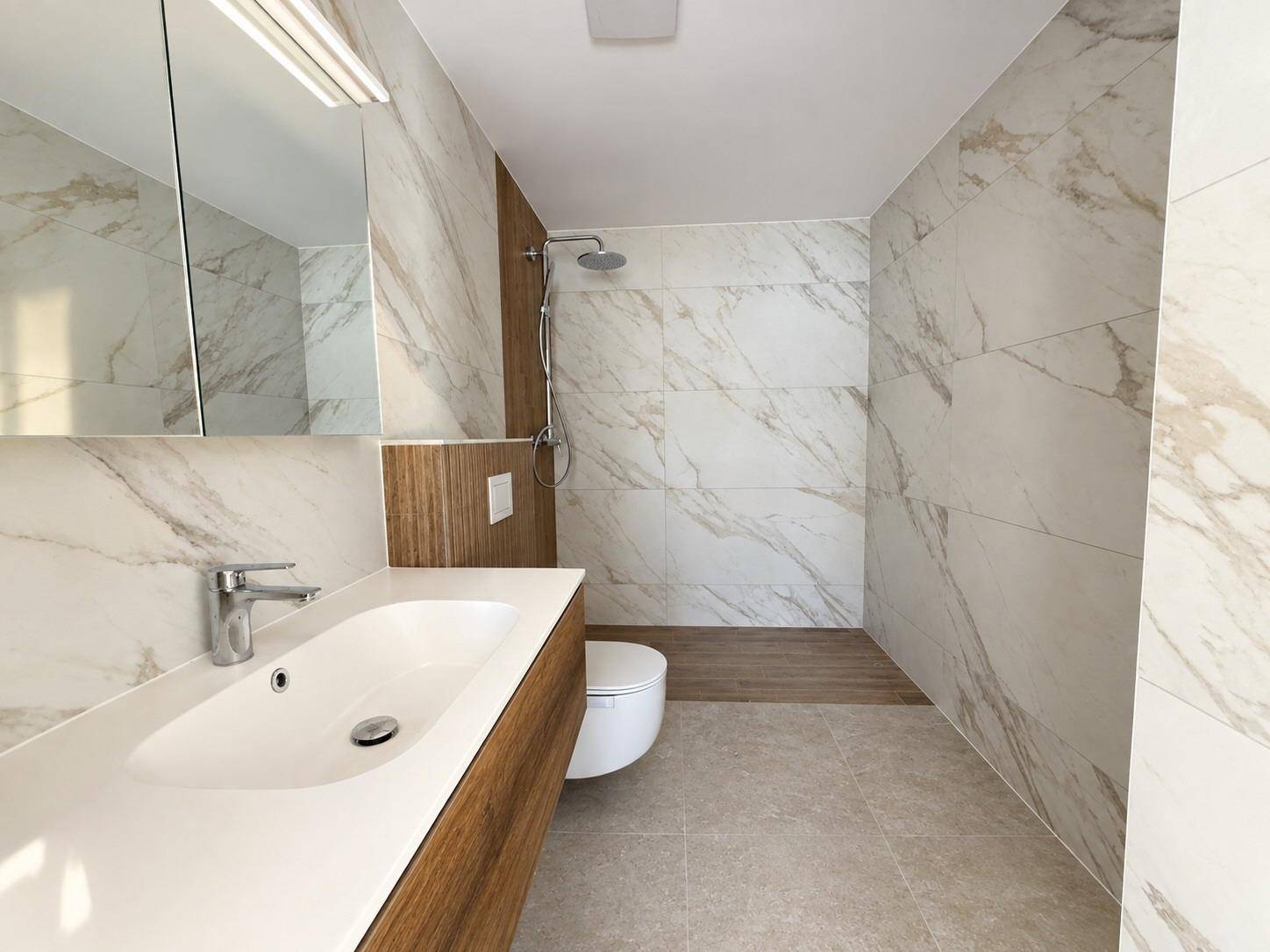 Modernes Badezimmer mit großformatigen Marmorfliesen, ebenerdiger Dusche und elegantem Waschtisch.