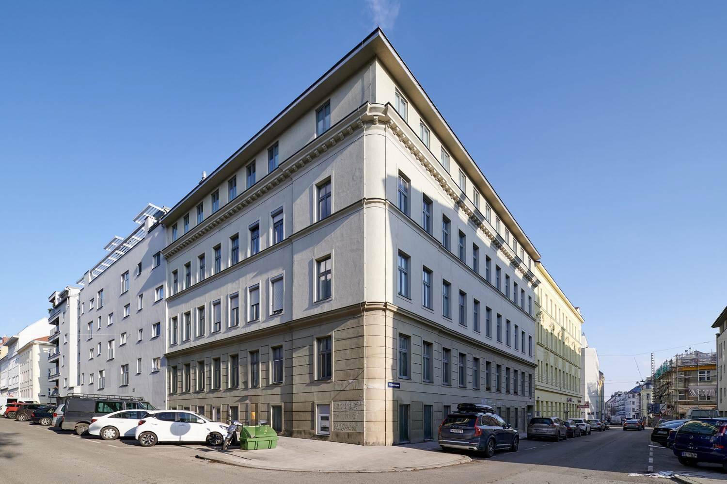 Eckgebäude mit klassischer Fassade und vielen Fenstern an einer städtischen Straße.