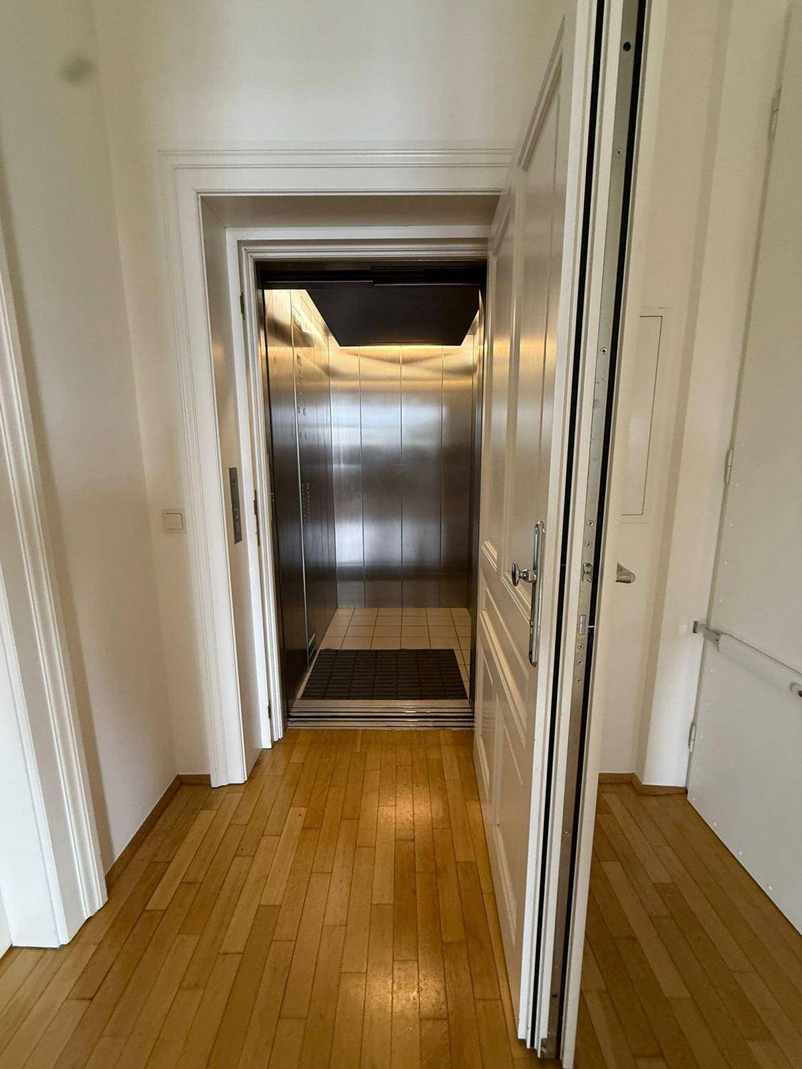 Heller Flur mit Parkettboden und Zugang zu einem modernen Aufzug.
