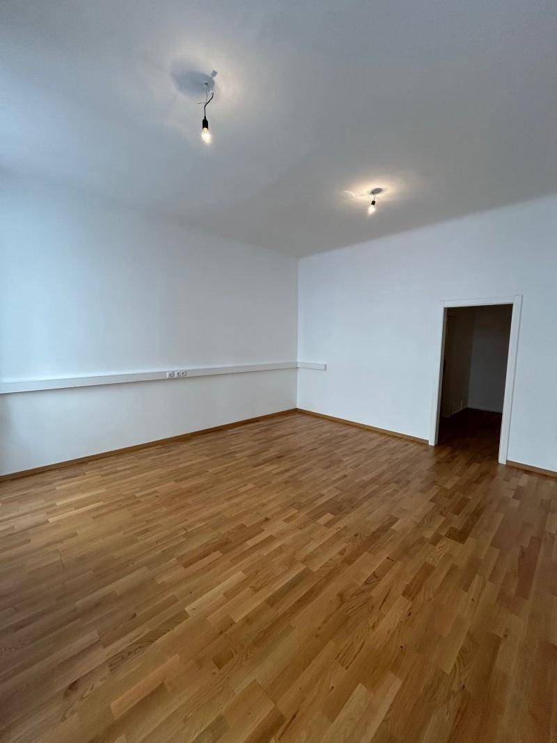 Heller Raum mit Holzboden und weißen Wänden, ideal als Wohn- oder Arbeitsbereich.