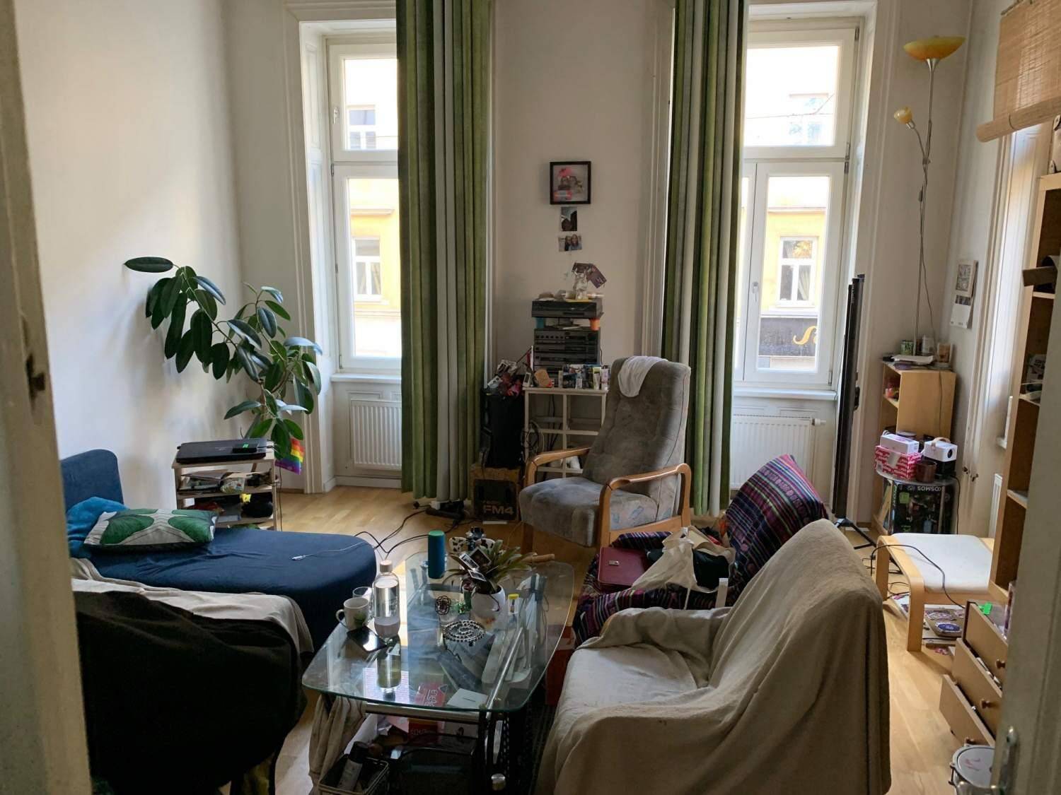 Geräumiges Wohnzimmer mit Holzboden, großen Fenstern und gemütlichen Sitzgelegenheiten für Entspannung.