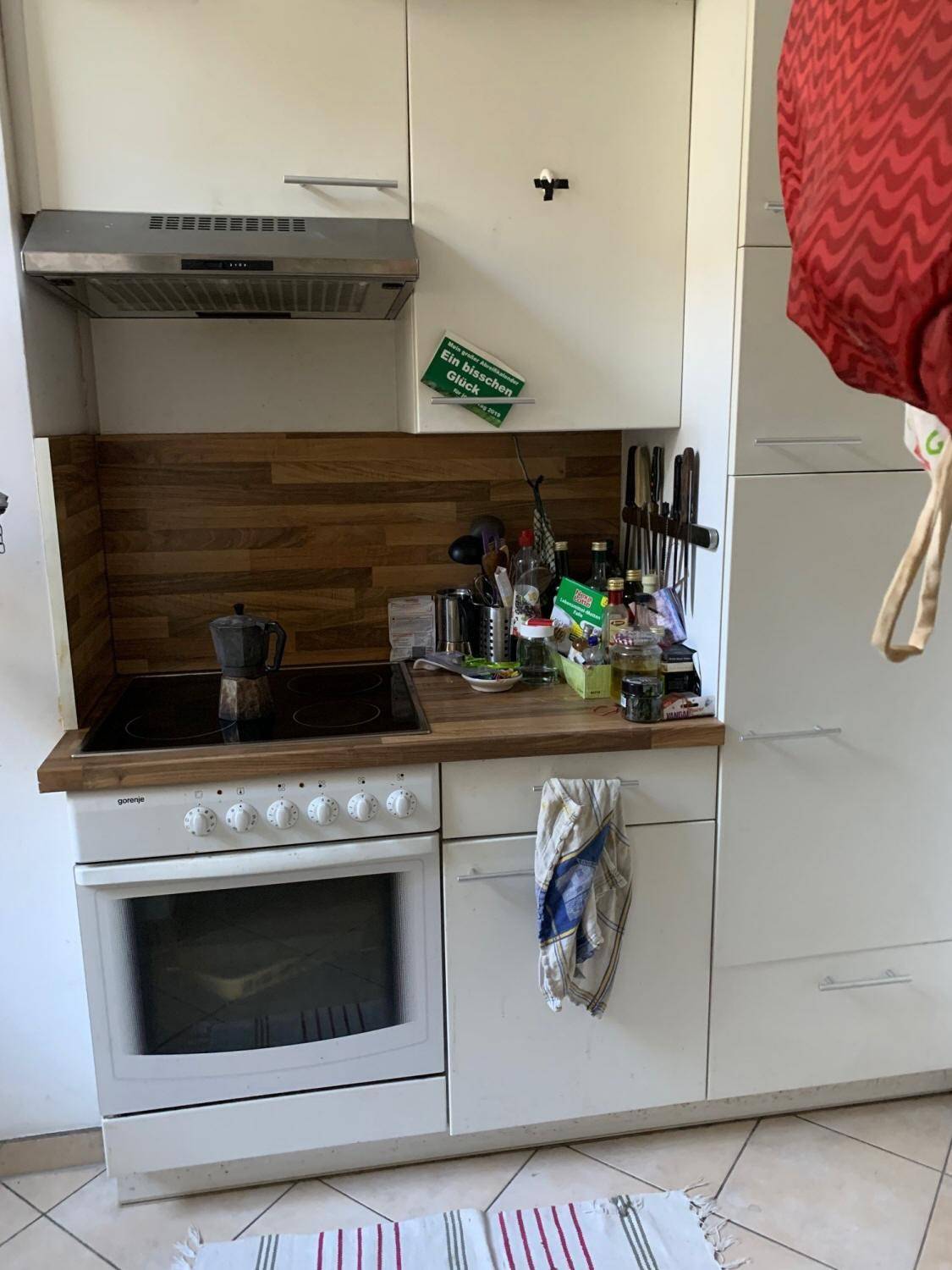 Kompakte Küche mit Herd, Backofen und Holz-Arbeitsplatte in hellem Design für effizientes Kochen.