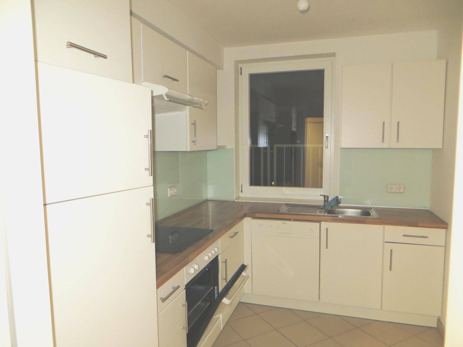 Funktionale Küche mit weißen Fronten, Fenster und integriertem Geschirrspüler.