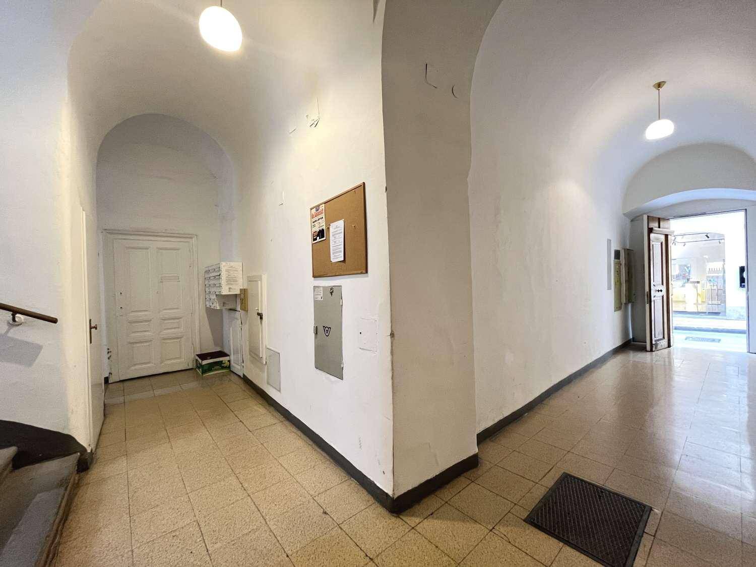 Eingangsbereich eines Altbaus mit gewölbten Decken und Fliesenboden, der zu den Wohnungen führt.