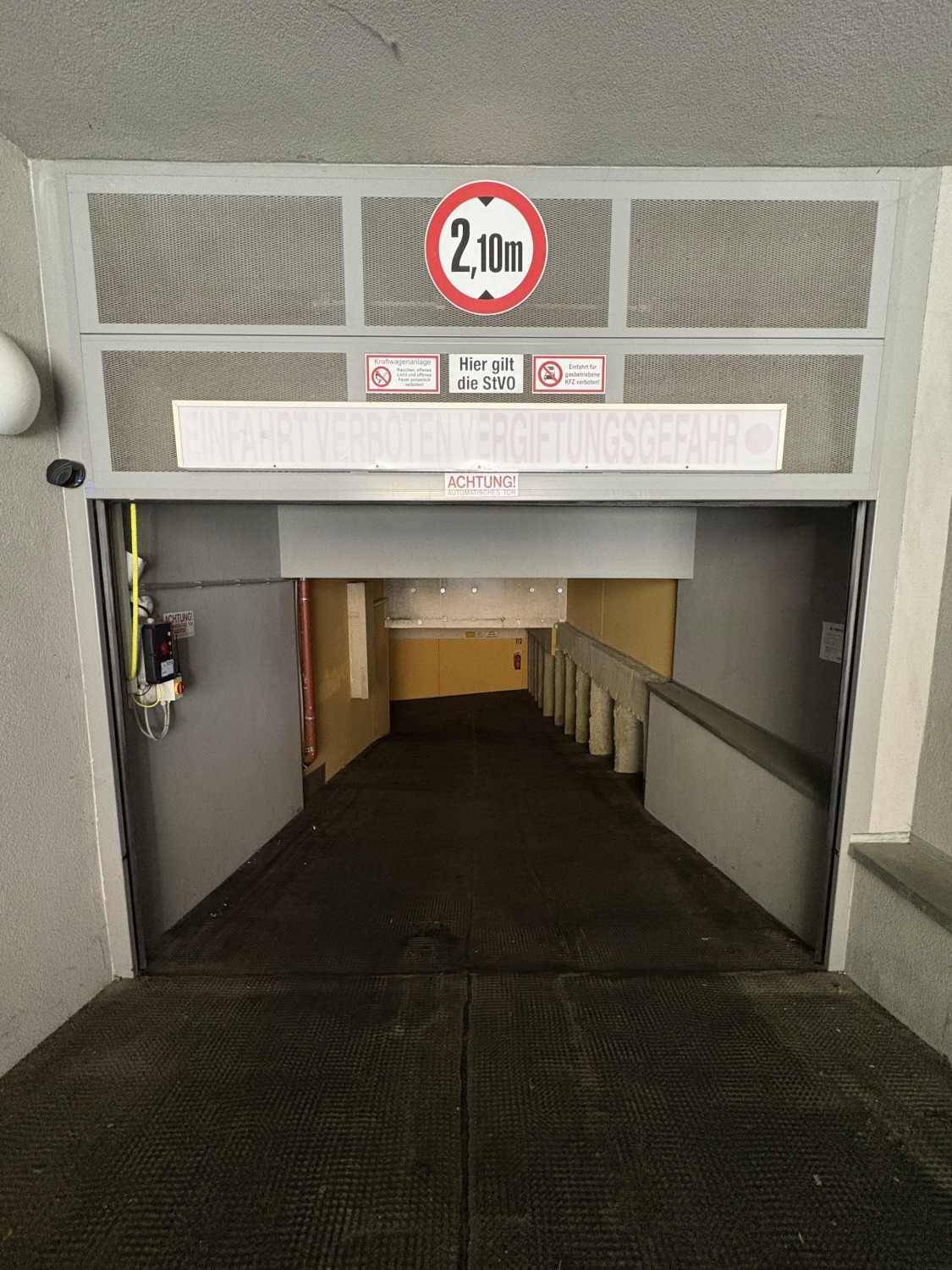 Einfahrt zu einer Tiefgarage mit Rampe und deutlicher Höhenbegrenzung von 2,10 Metern.