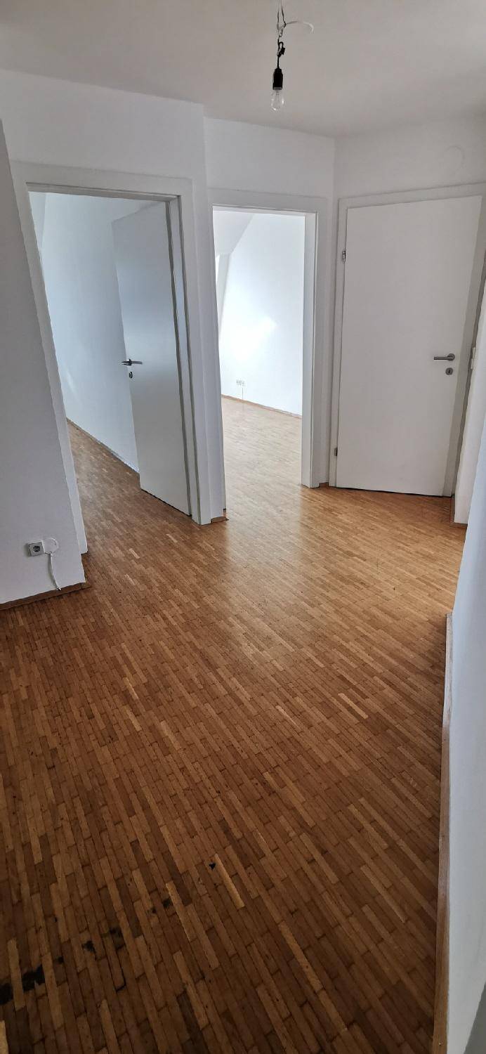 Geräumiger Flur mit Holzparkettboden und mehreren Türen, der verschiedene Räume verbindet.