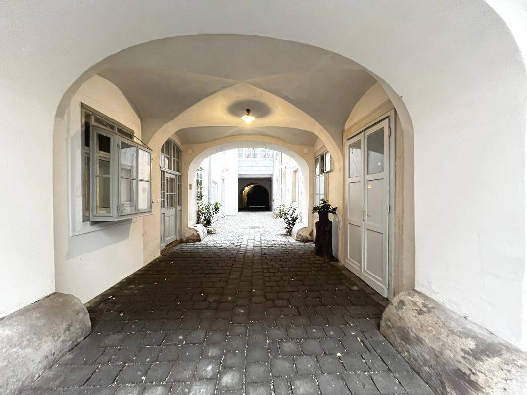 Langer, gewölbter Durchgang mit Kopfsteinpflaster, der tiefer in den Gebäudekomplex führt.