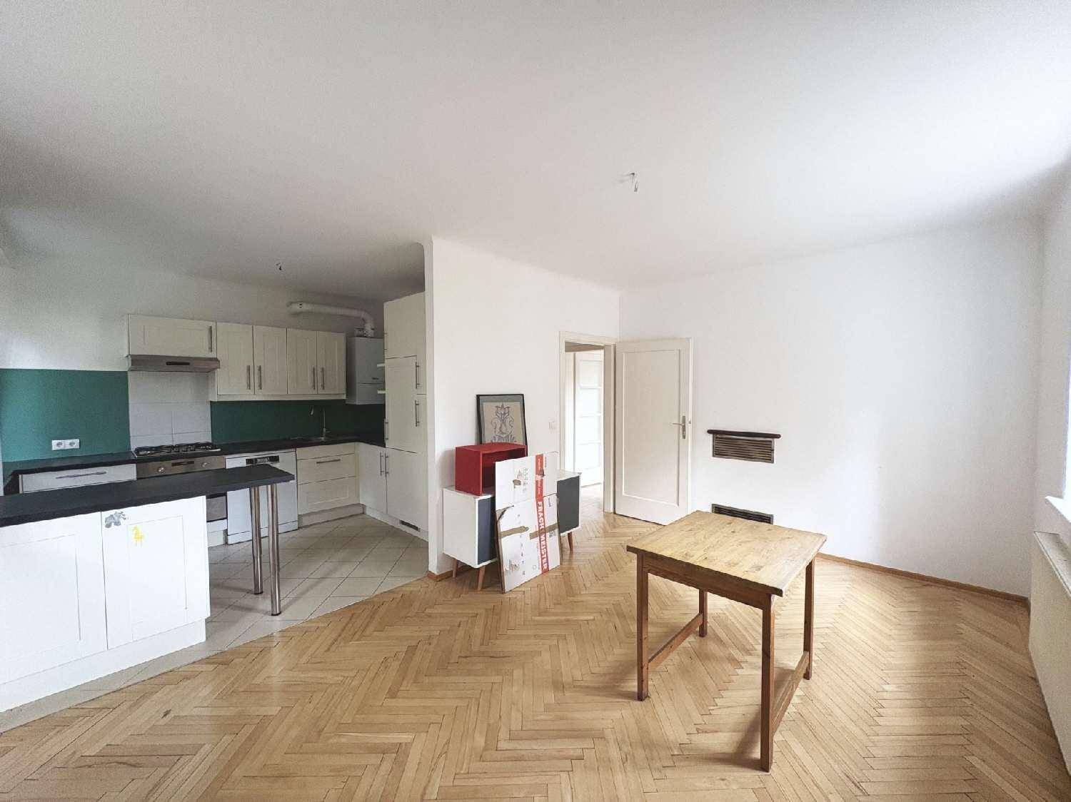 Offener Wohnbereich mit integrierter Küche und Fischgrätparkettboden.