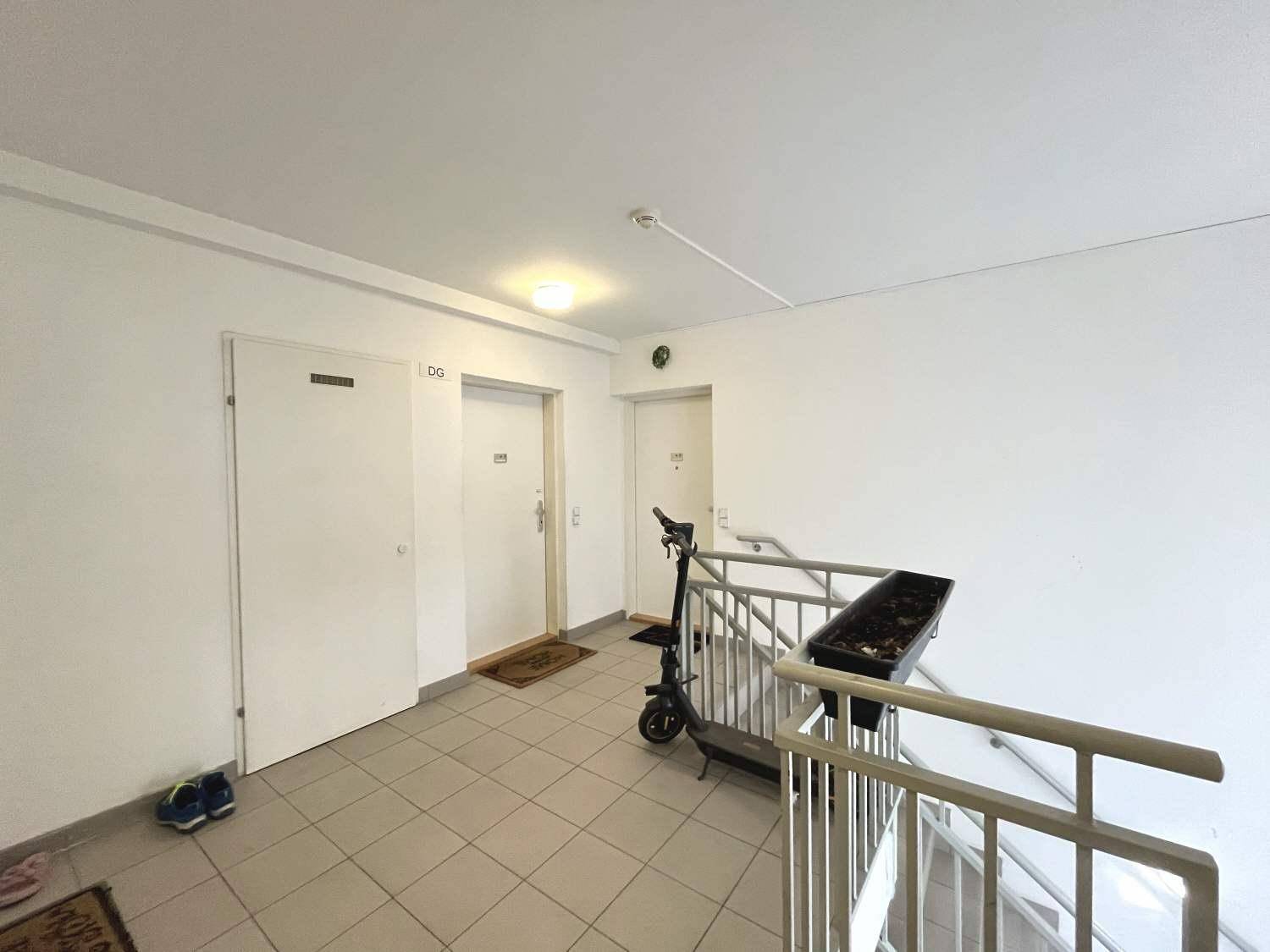 Oberes Treppenhaus mit Fliesenboden und Türen zu den Wohnungen, ausgestattet mit einem Rauchmelder.