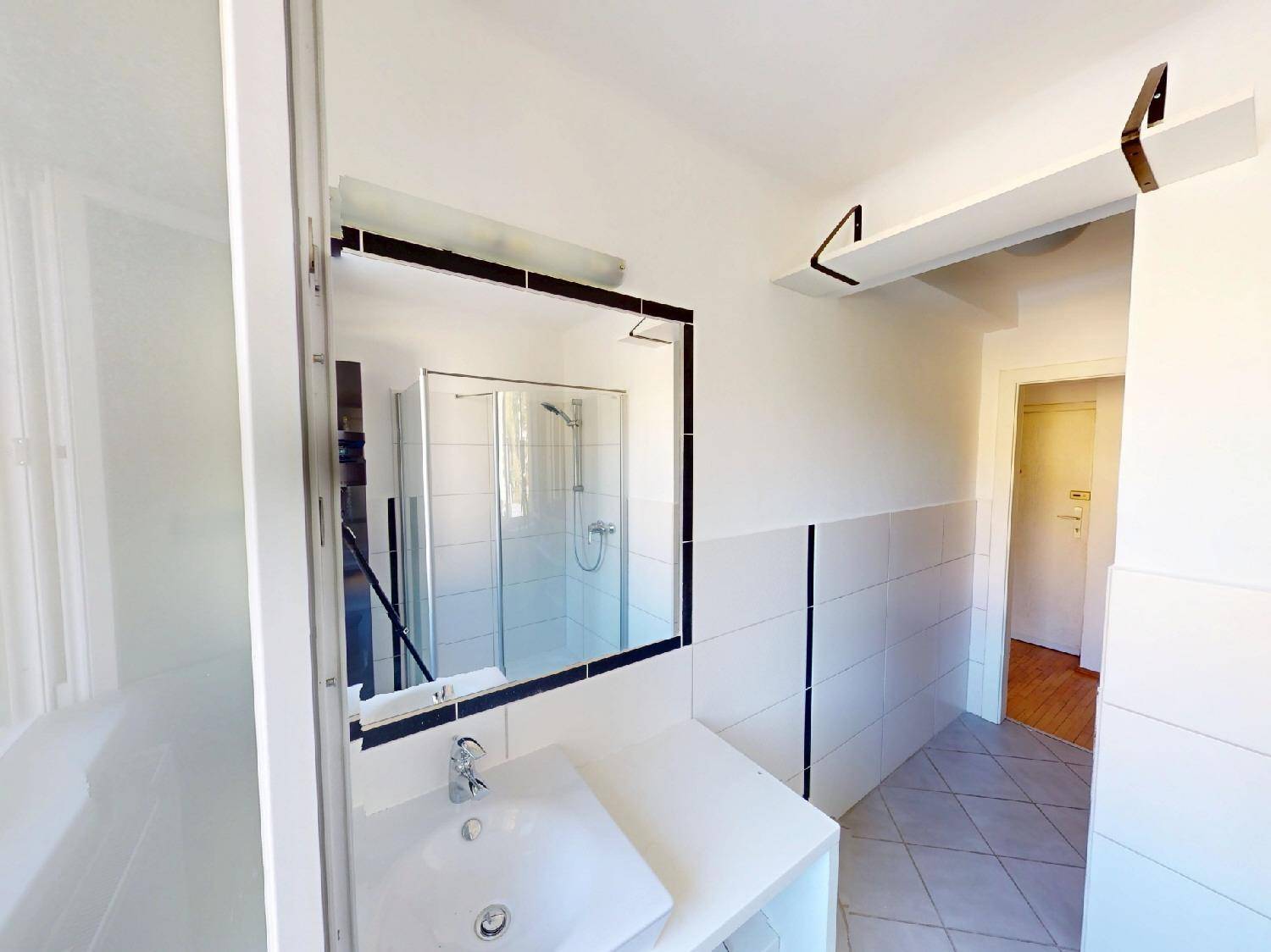 Modernes Badezimmer mit Dusche, Waschbecken und Spiegel, hell gefliest.