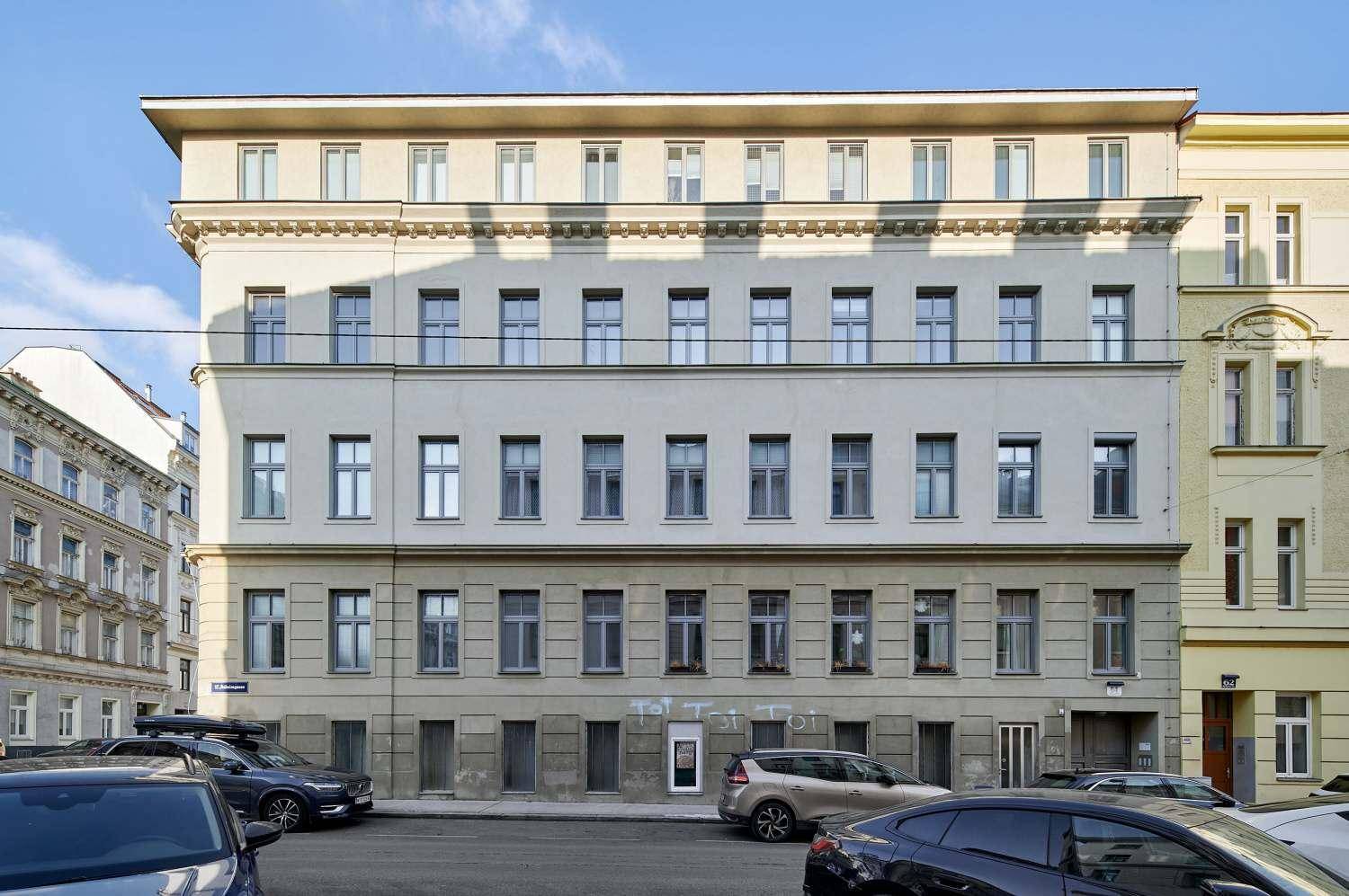 Gebäudefassade mit vielen Fenstern und einem Flachdach an einer städtischen Straße.
