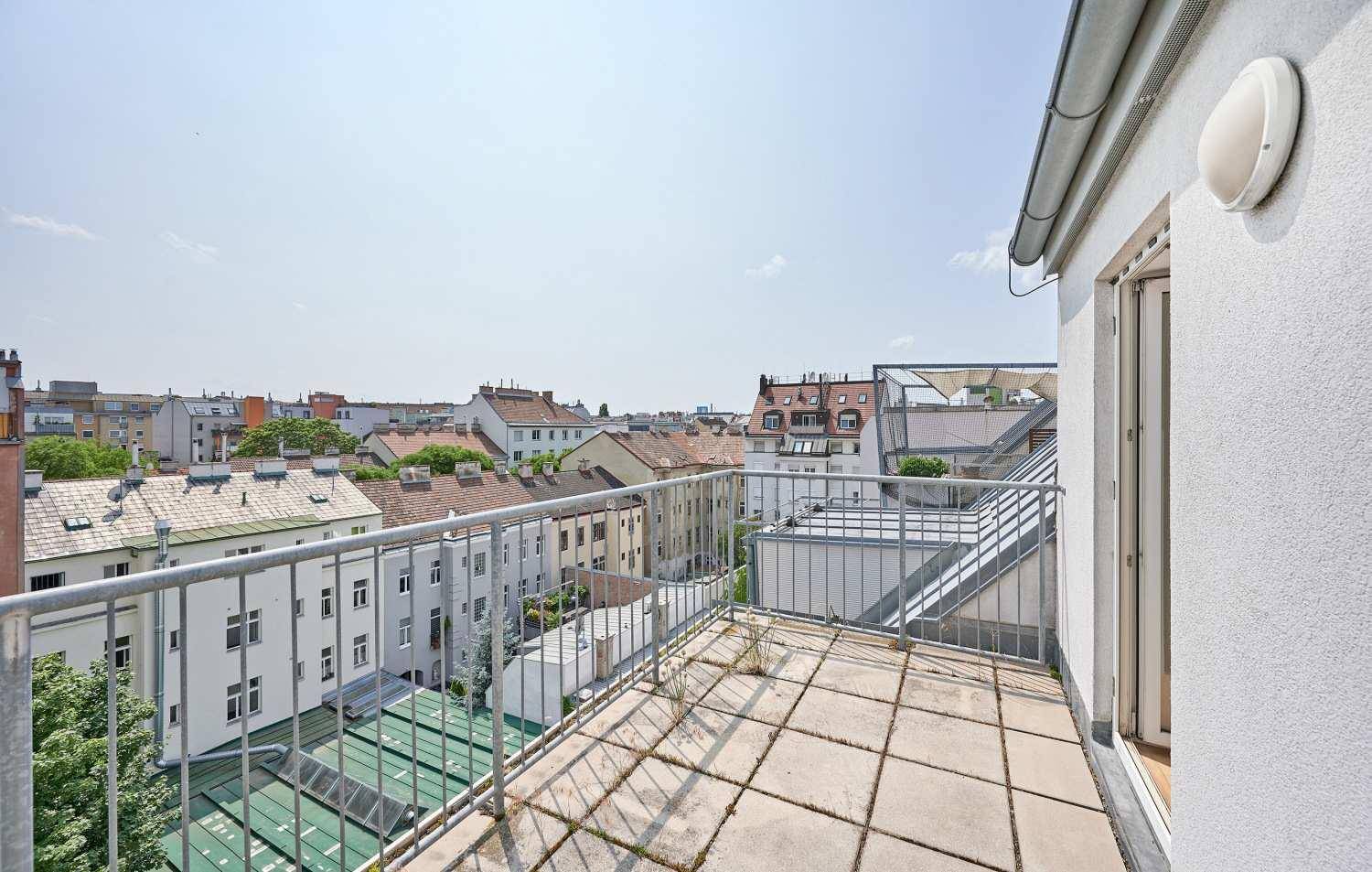Geräumiger Balkon mit Fliesenboden und Metallgeländer, der einen weiten Blick über die Stadt bietet.