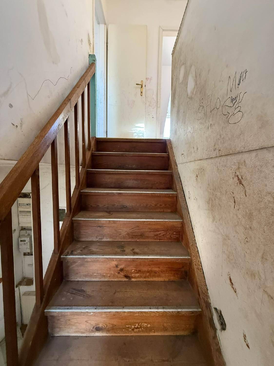 Holztreppe mit Geländer, die in die oberen Stockwerke des Hauses führt.
