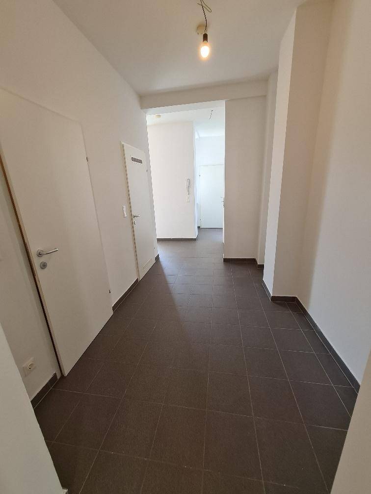 Langer, heller Flur mit Fliesenboden und Zugang zu mehreren Zimmern der Wohnung.
