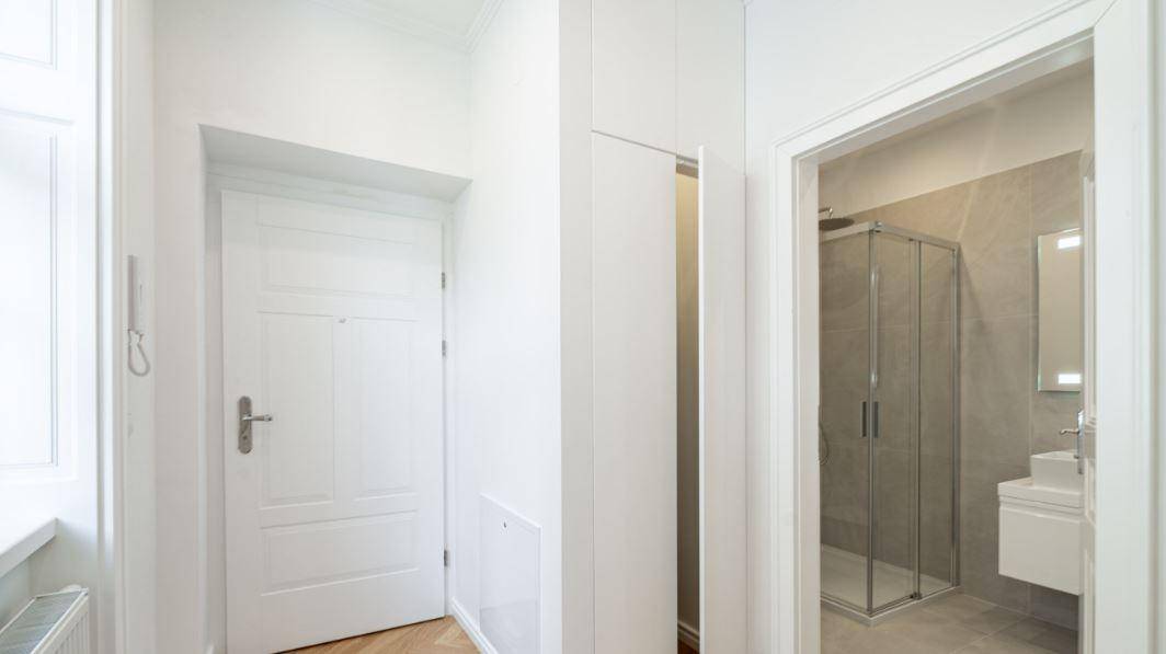 Eingangsbereich mit weißer Tür, Einbauschrank und Blick in das moderne Badezimmer.