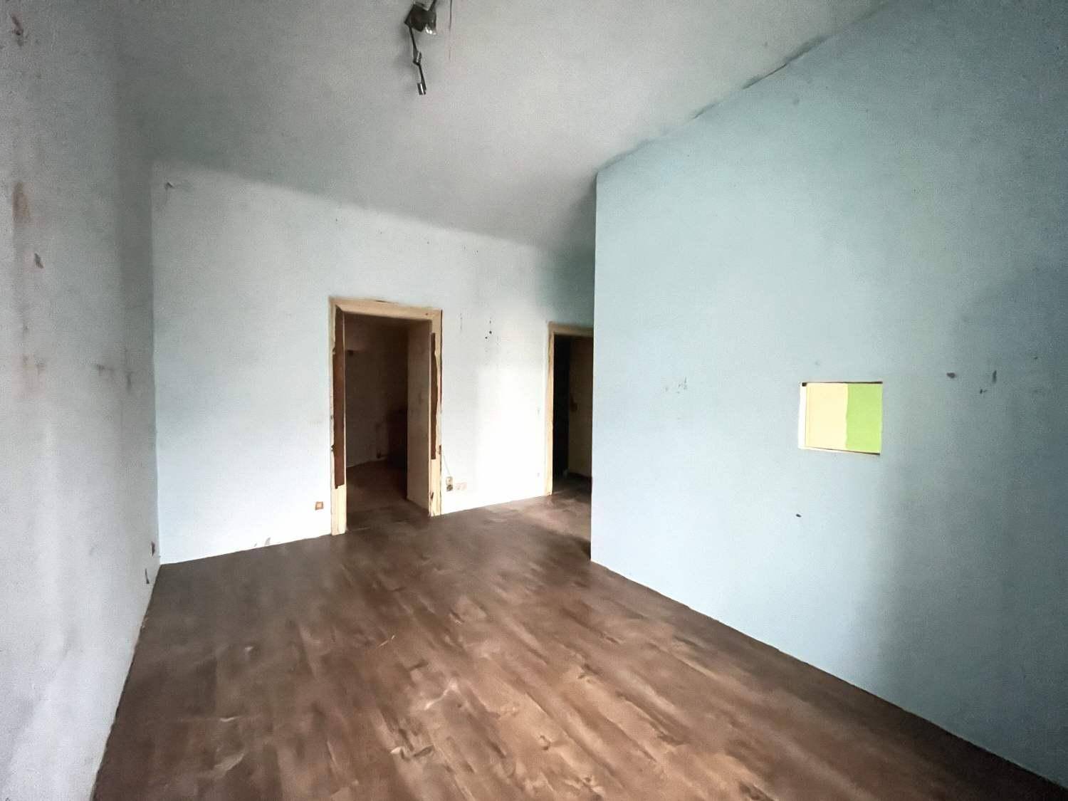 Unmöblierter Raum mit Holzboden und zwei Türöffnungen, bereit zur Renovierung.