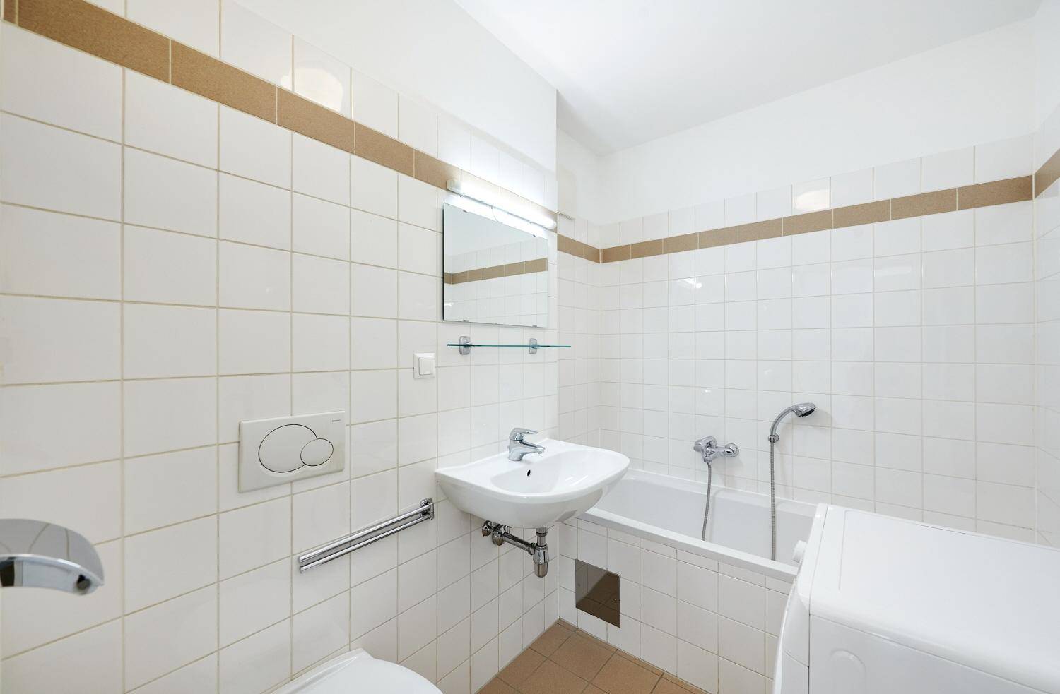 Funktionales Badezimmer mit Badewanne, wandhängendem WC und Waschmaschine, hell gefliest.