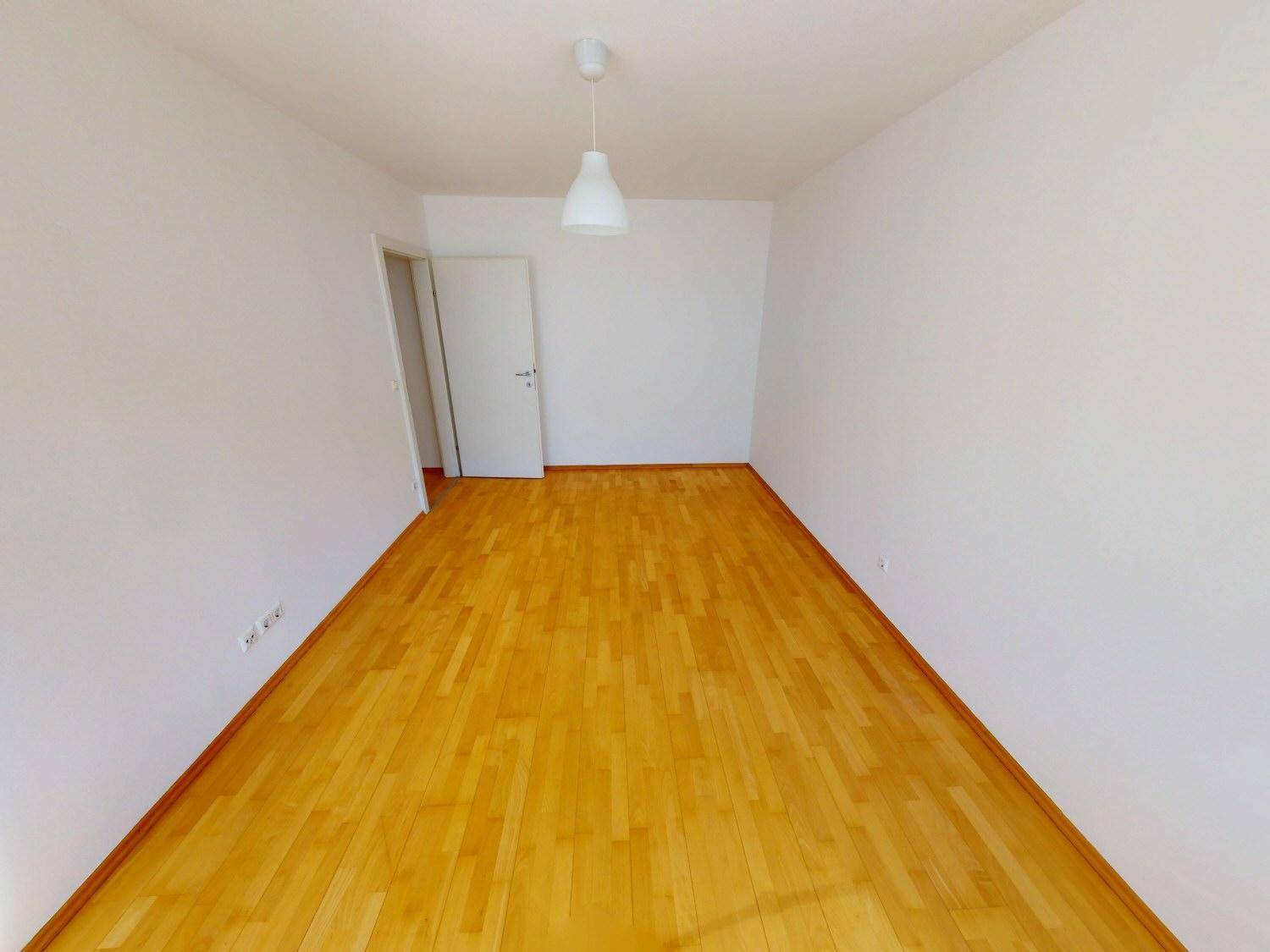Leeres Zimmer mit hellem Parkettboden und weißen Wänden, bereit zur individuellen Gestaltung.