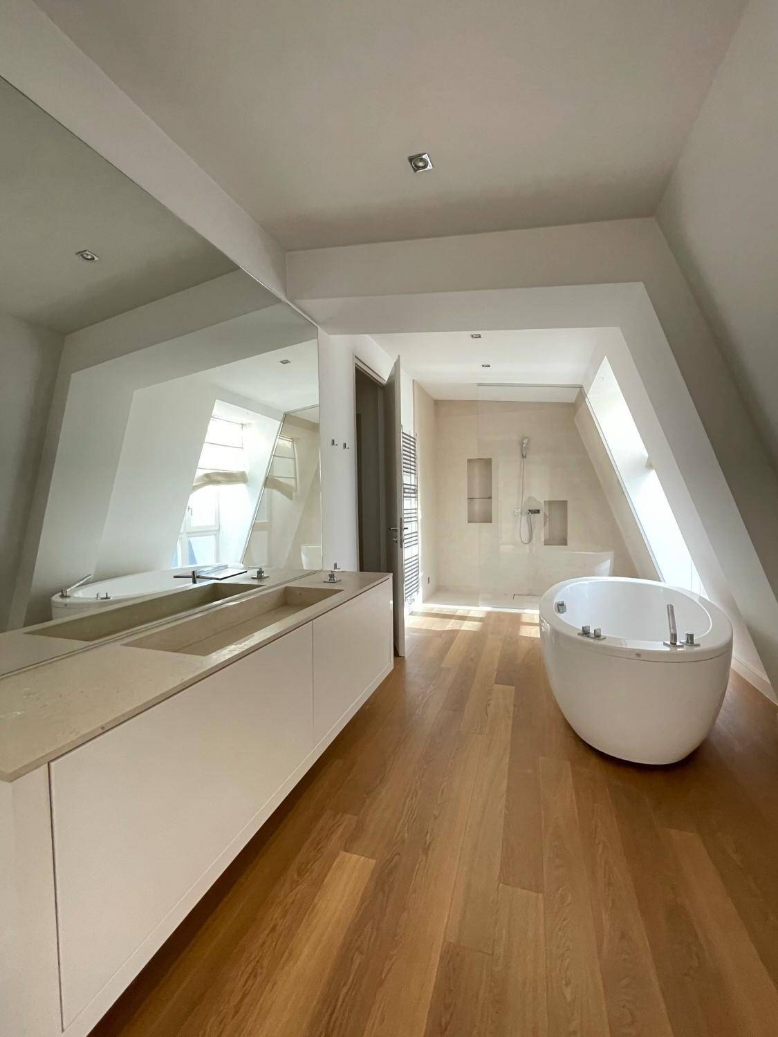 Modernes Badezimmer mit freistehender Badewanne, Doppelwaschbecken und separater Dusche unter Dachschrägen.