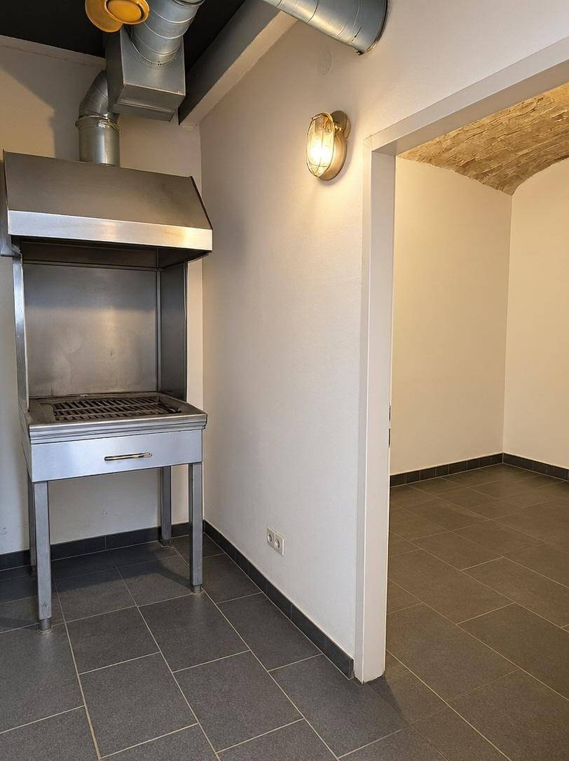 Raum mit einem großen Edelstahlgrill und Zugang zu einem weiteren Bereich.