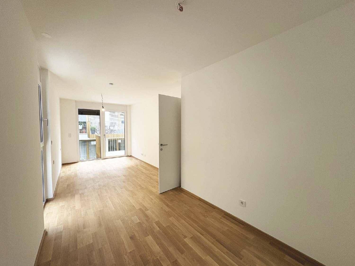 Heller Wohnbereich mit Holzboden und Zugang zu einem Balkon, ideal für entspannte Stunden.