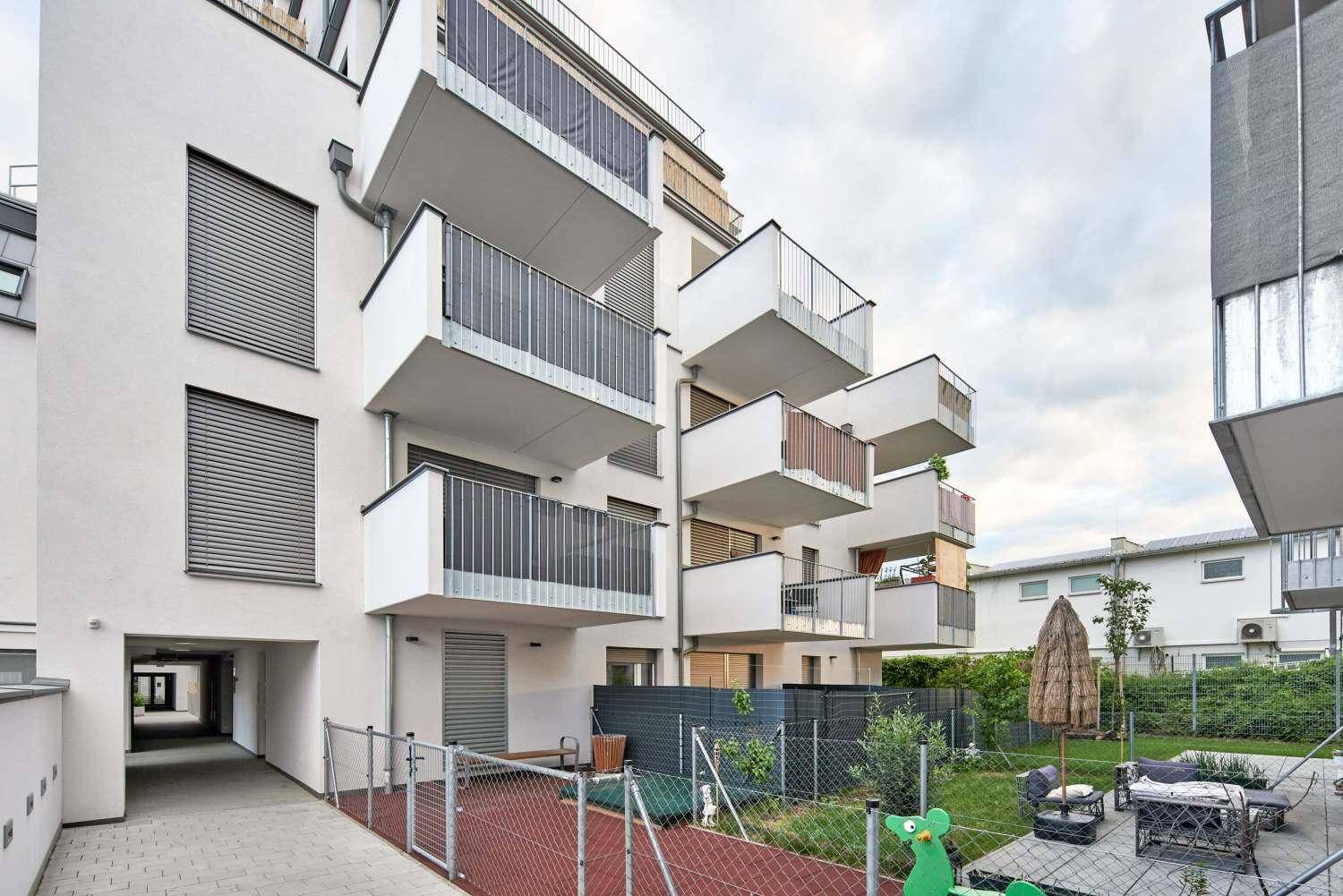 Außenansicht des Gebäudes mit einem kleinen Gartenbereich und Sitzgelegenheiten.