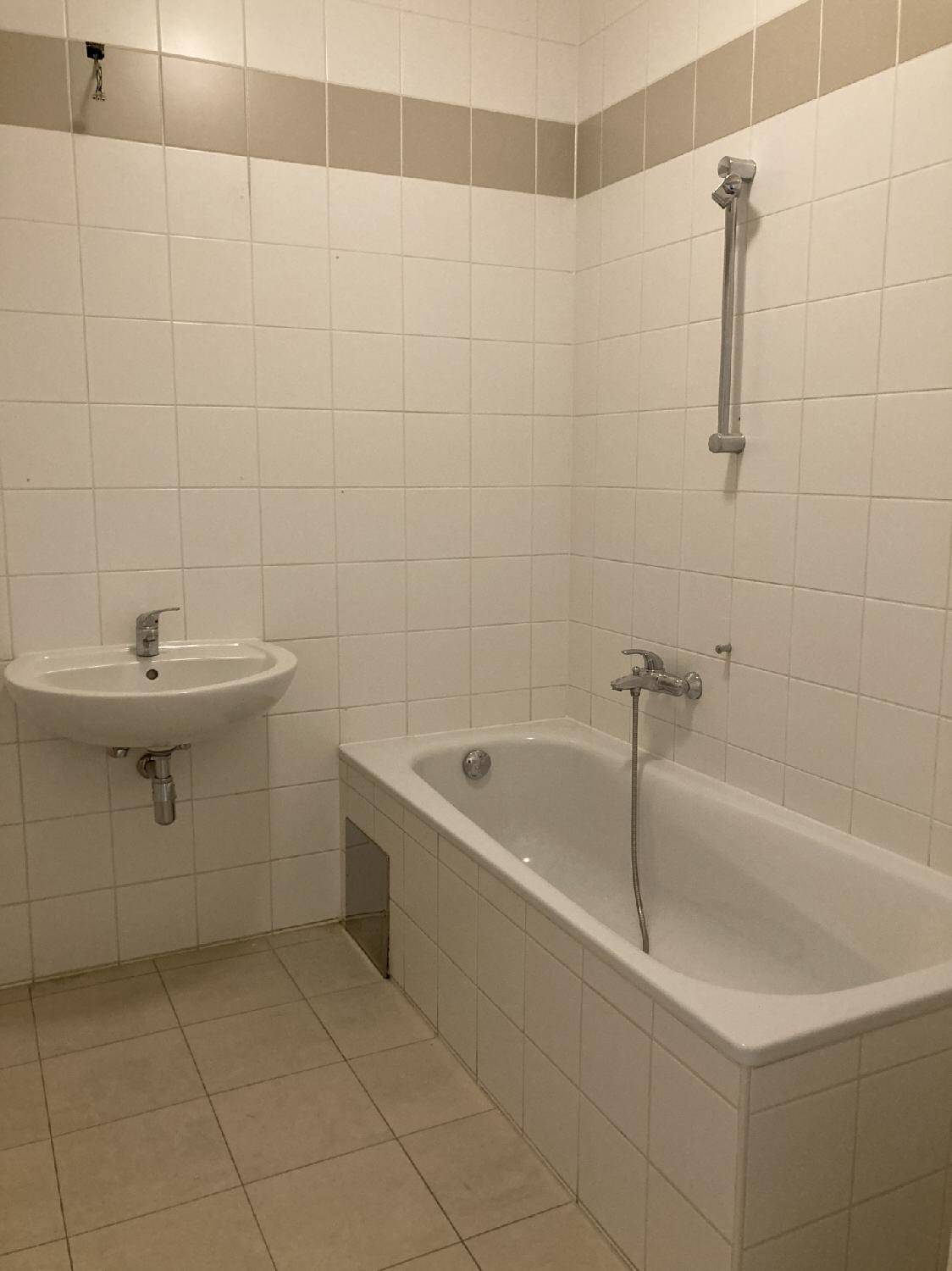 Gefliestes Badezimmer mit Badewanne, Waschbecken und Duschvorrichtung.