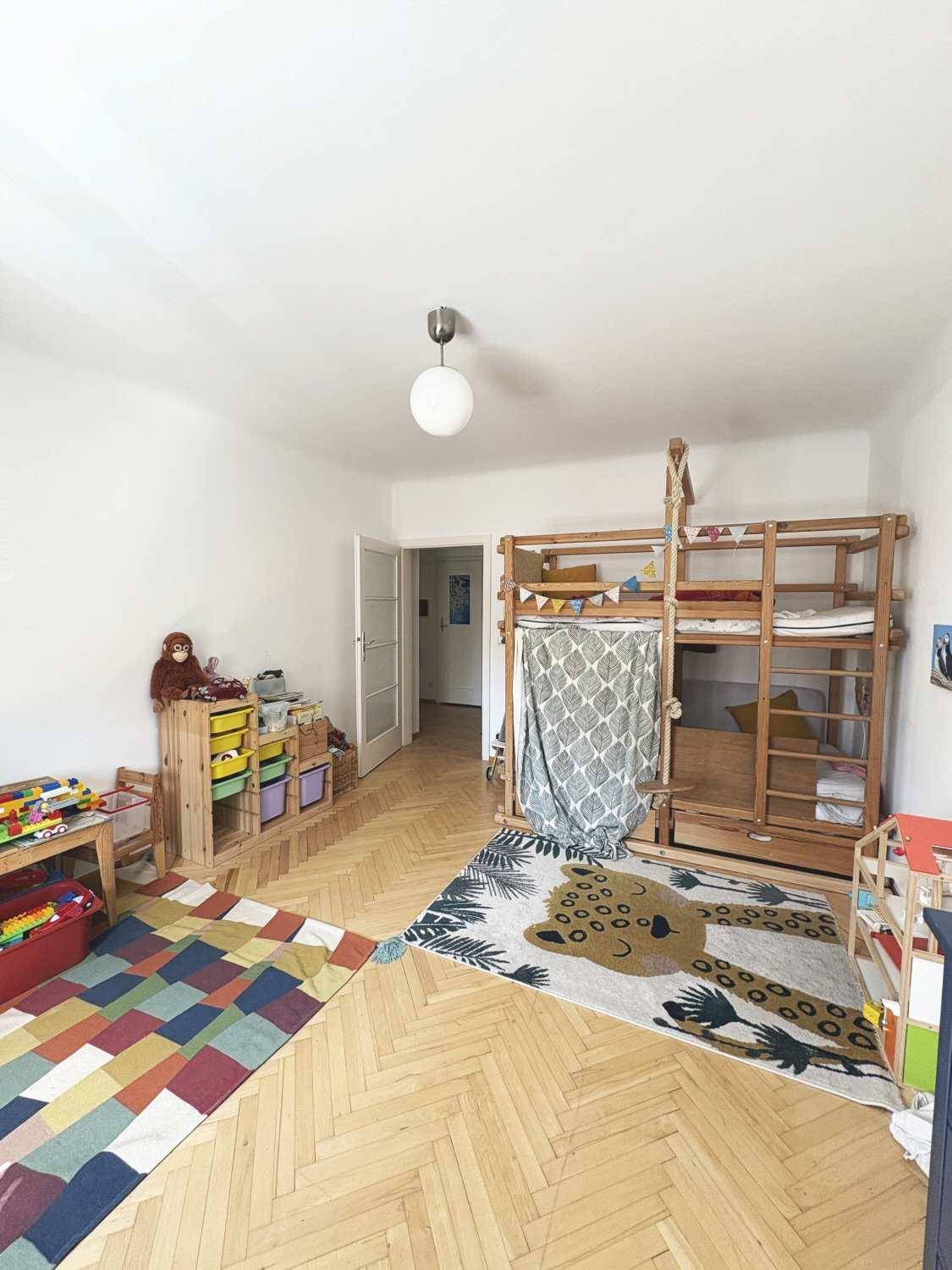 Kinderzimmer mit Hochbett, Spielteppichen und Fischgrätparkettboden.