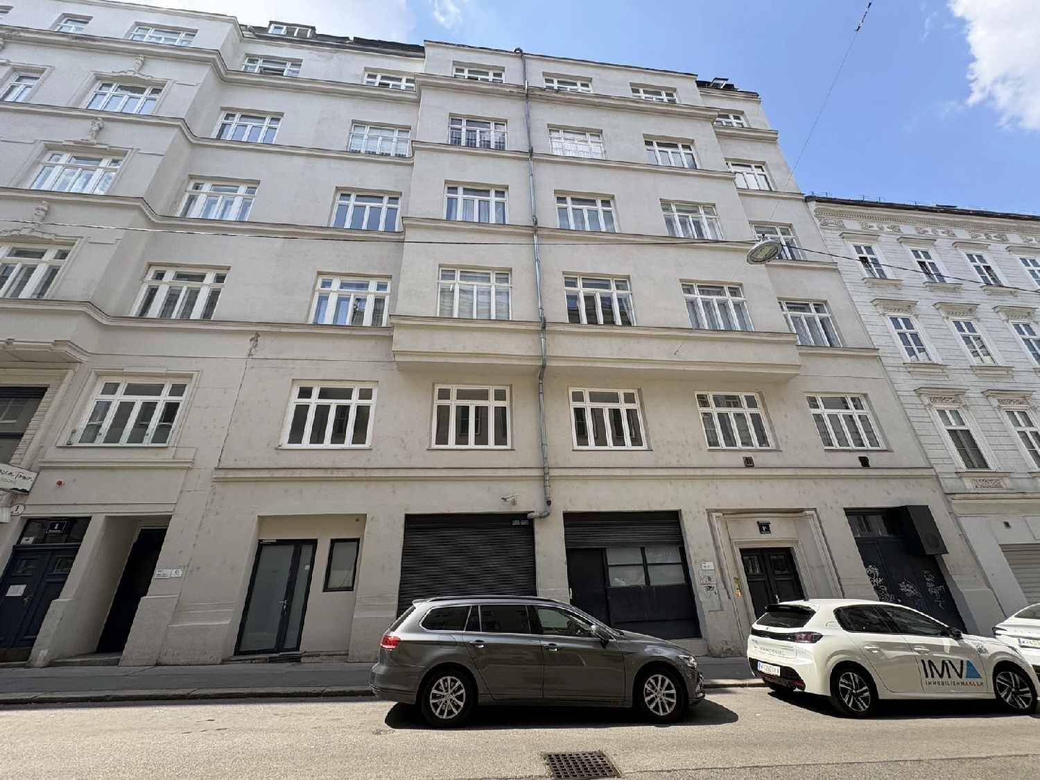Historische Gebäudefassade mit vielen Fenstern und Geschäften im Erdgeschoss an einer Stadtstraße.