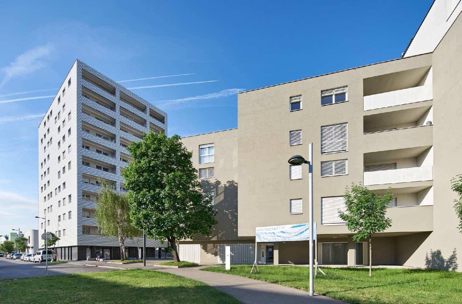 Moderne Wohnanlage mit verschiedenen Gebäudetypen und Grünflächen unter klarem Himmel.